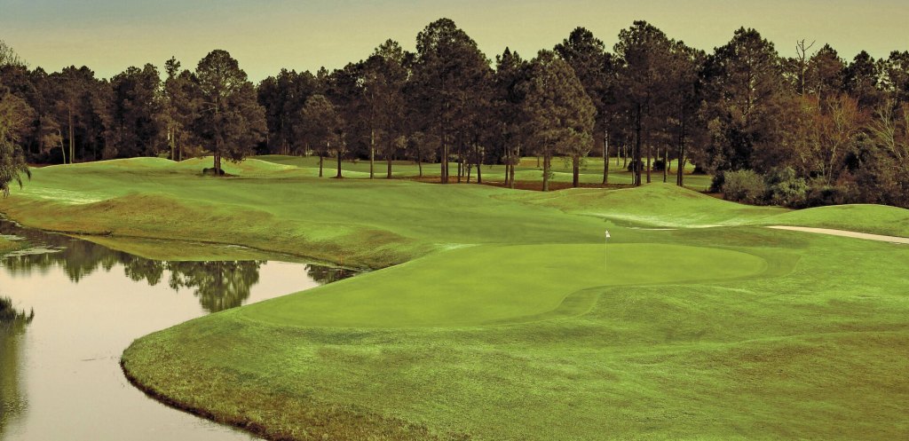 View of golf course with path, trees, and pond 